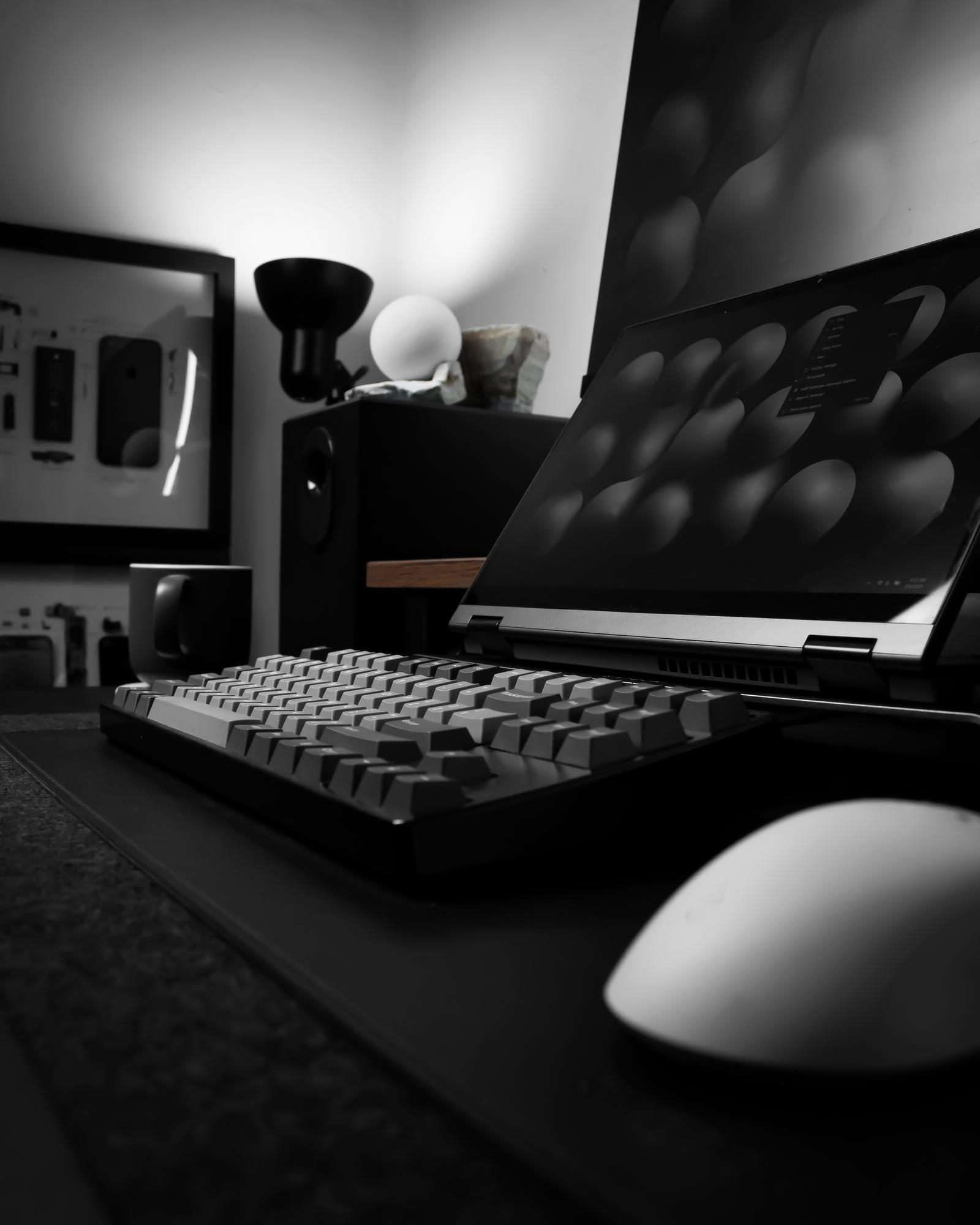 A sleek black-and-white workspace setup featuring a laptop, keyboard, and mouse under moody lighting, representing technology, precision, and AI-driven creativity in modern marketing.