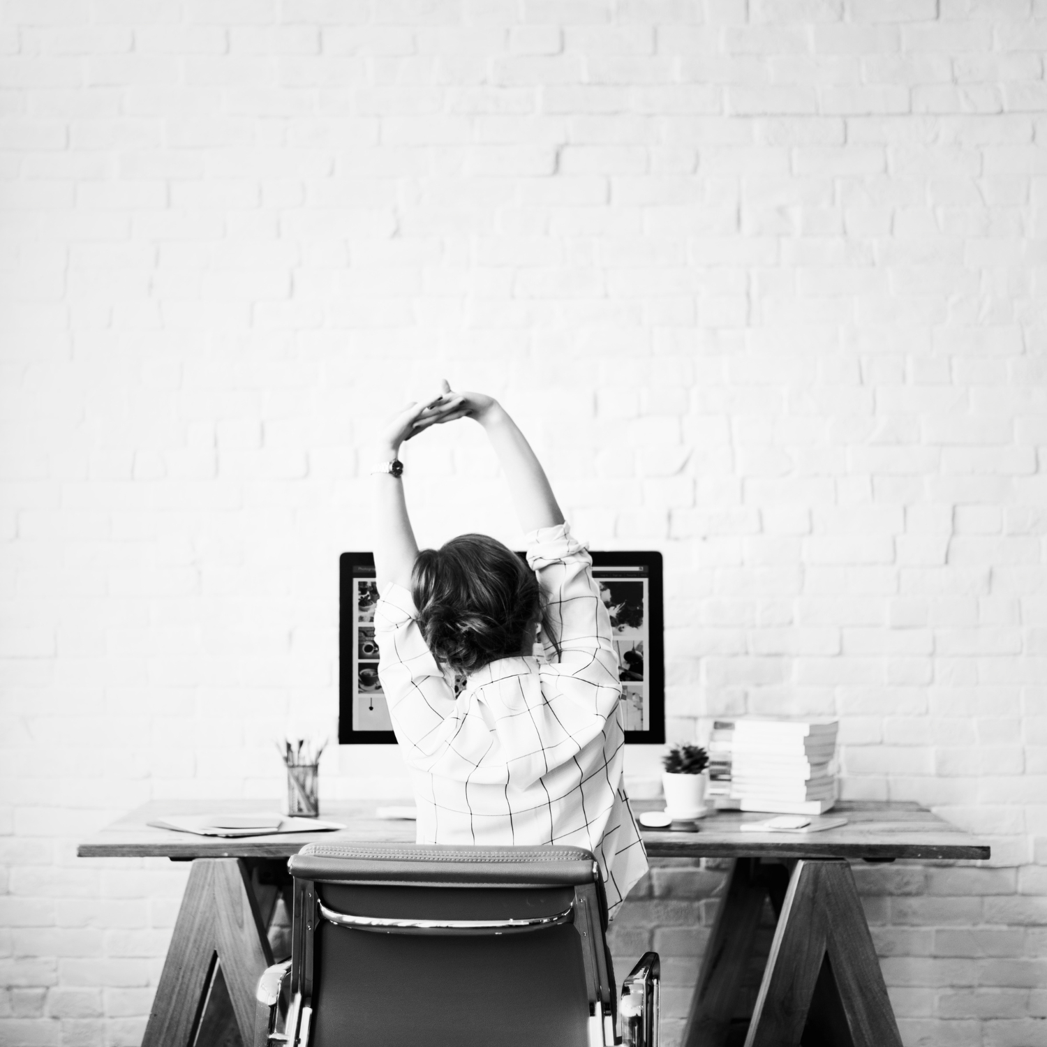A woman stretching in front of her computer at a minimalist creative workspace, symbolizing balance, clarity, and thoughtful strategy in modern marketing.
