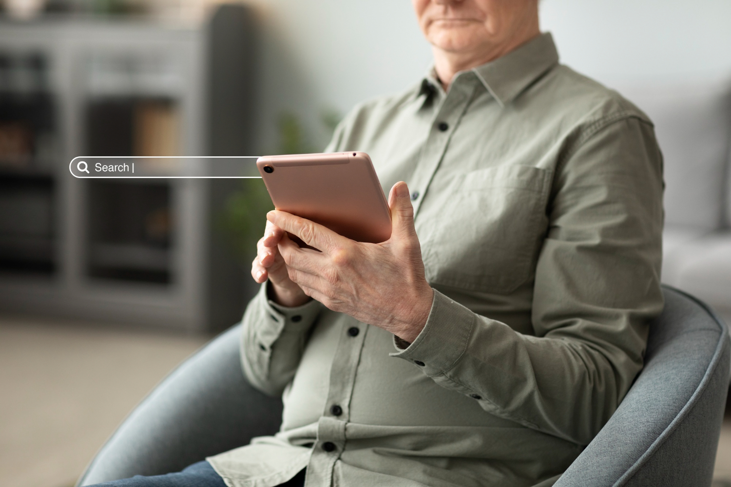 A person holding a coffee mug while using a laptop on their lap, seated on a couch in a bright room.
